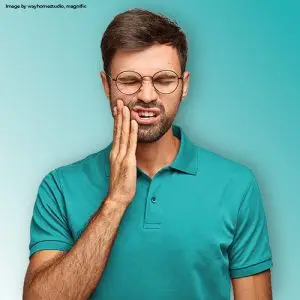 A man holding his jaw in discomfort due to a severe toothache, representing advanced complications and pain from untreated periodontal disease.